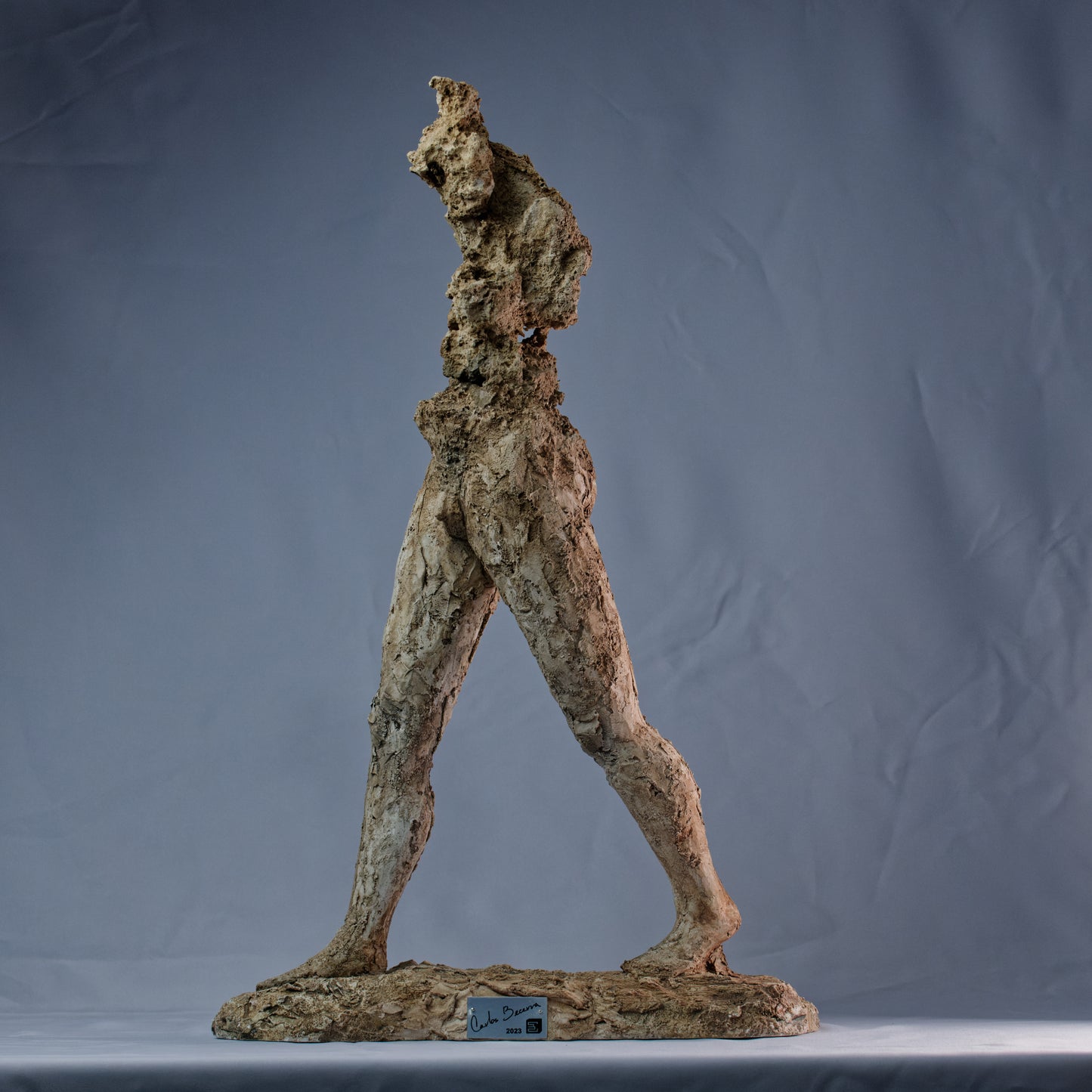Obra escultórica con figura erosionada y piernas firmes avanzando – El hombre que camina.