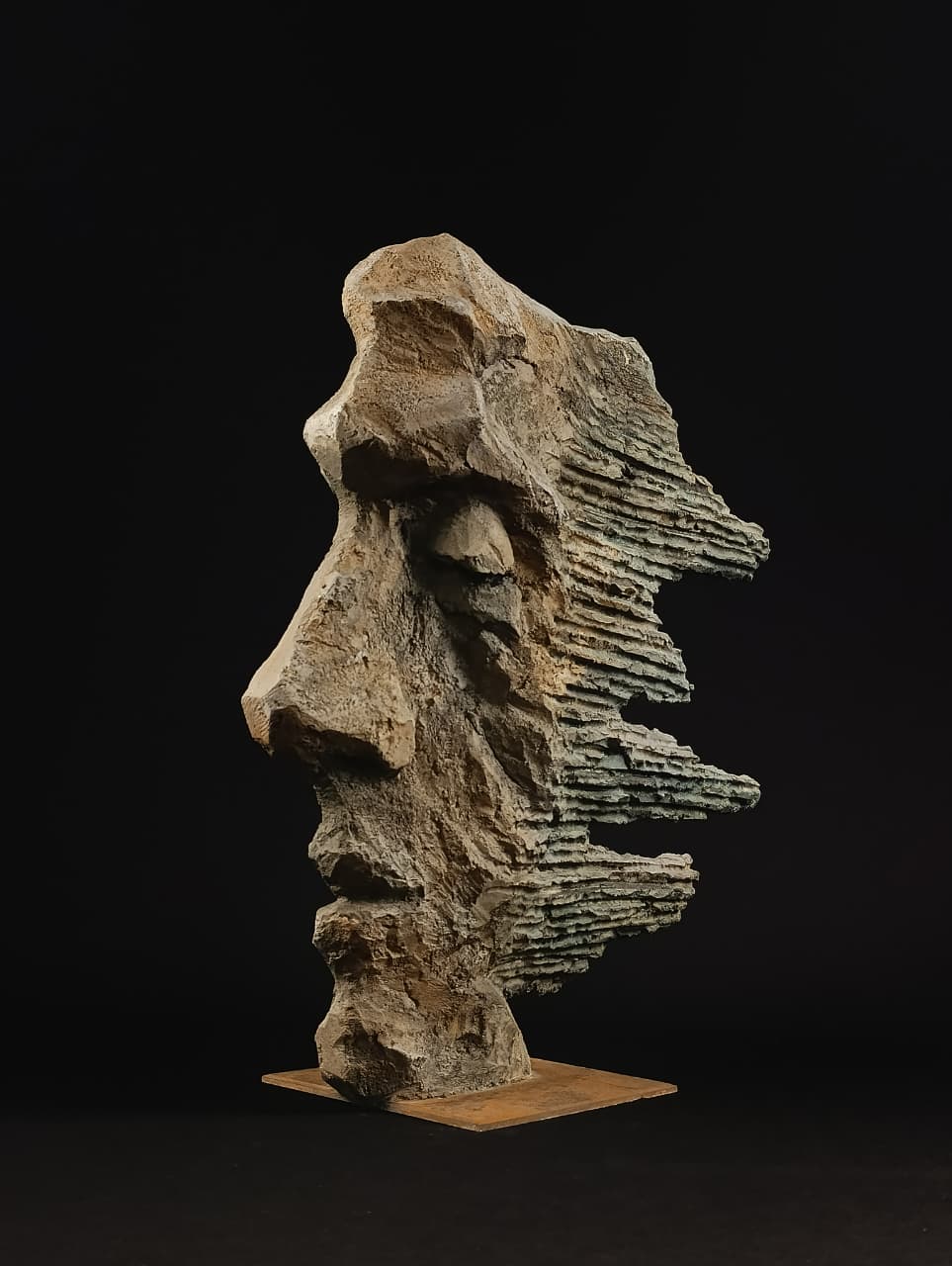 Cabeza masculina contemporánea en piedra con efecto erosionado y rasgos difusos.