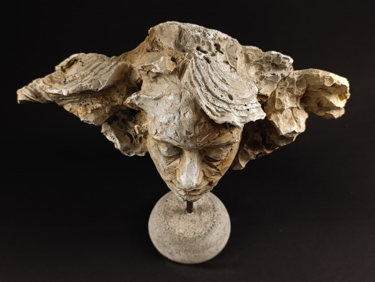 Vista cercana de la escultura en piedra artificial donde la roca orgánica se integra como parte del cabello humano.
