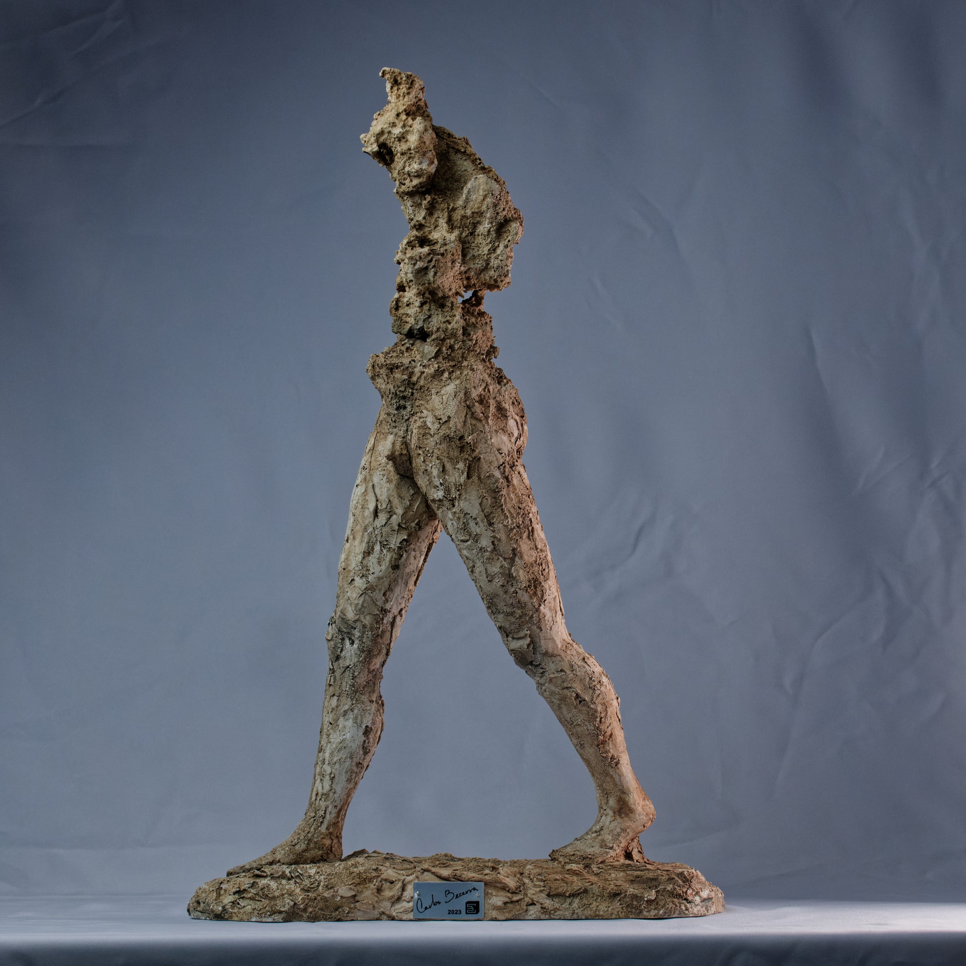 Obra escultórica con figura erosionada y piernas firmes avanzando – El hombre que camina.
