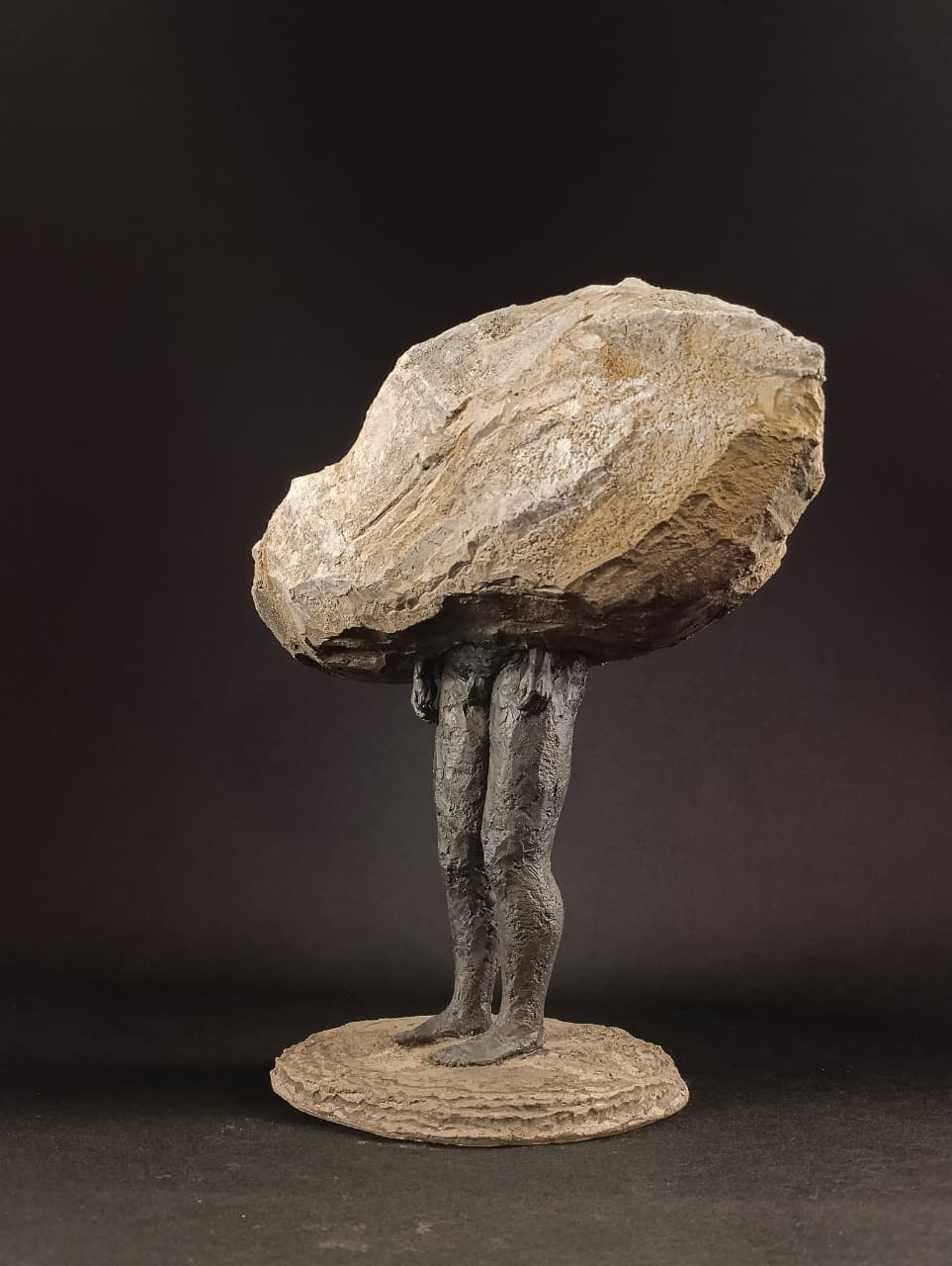 Escultura figurativa Sobrepeso, vista lateral completo, contraste entre cuerpo humano y roca