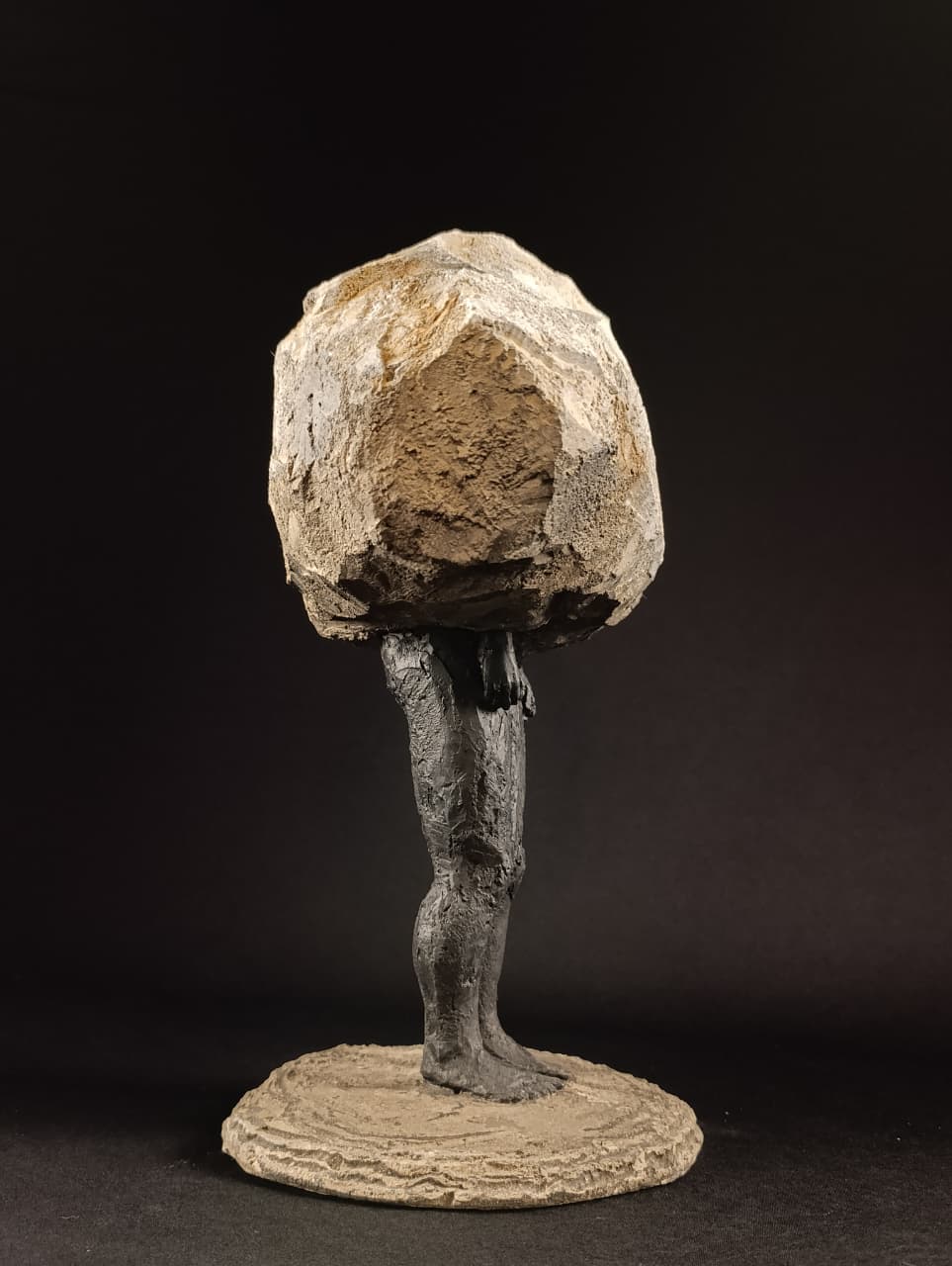 Escultura figurativa Sobrepeso, vista lateral, contraste entre cuerpo humano y roca