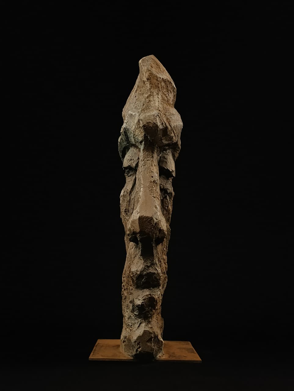 Rostro masculino en piedra con formas abstractas y rasgos humanos emergentes.