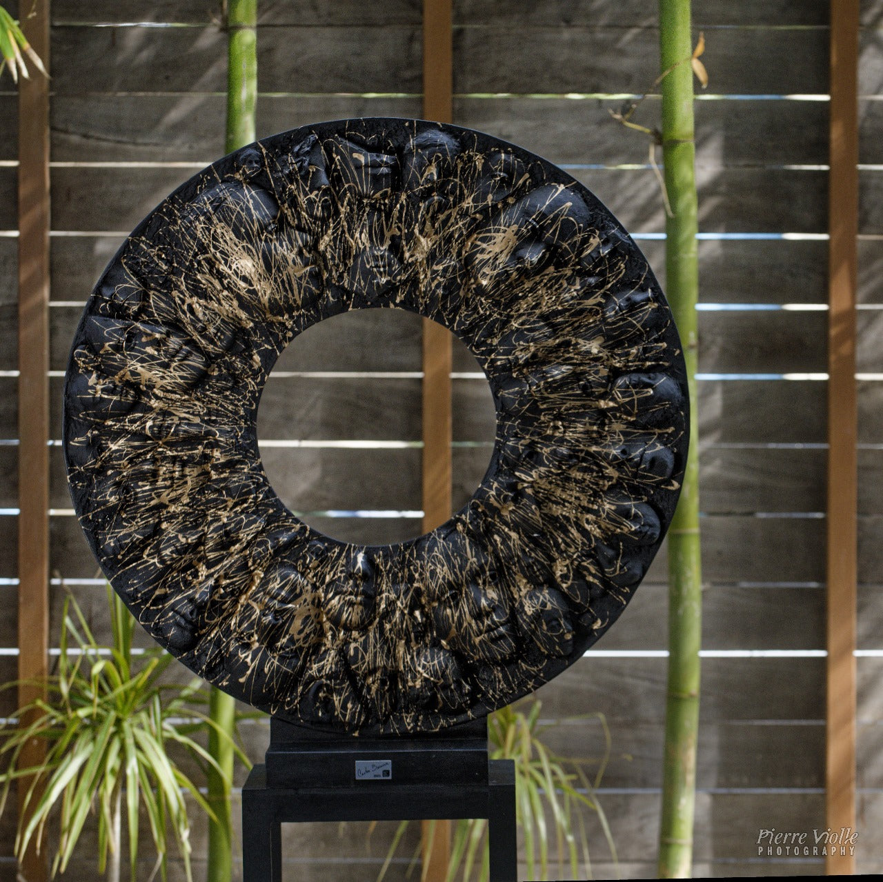 Vista frontal de Pupila, escultura contemporánea que evoca la forma de un ojo con figuras humanas.