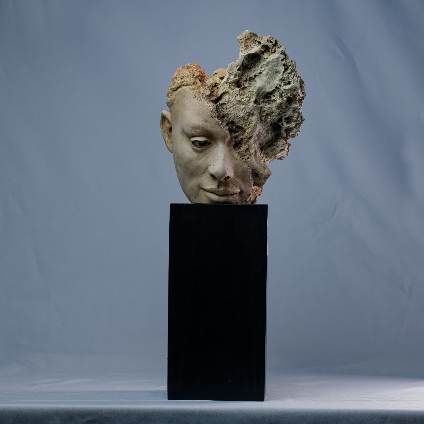 Obra escultórica contemporánea – mitad rostro humano, mitad roca con fragmentos de coral