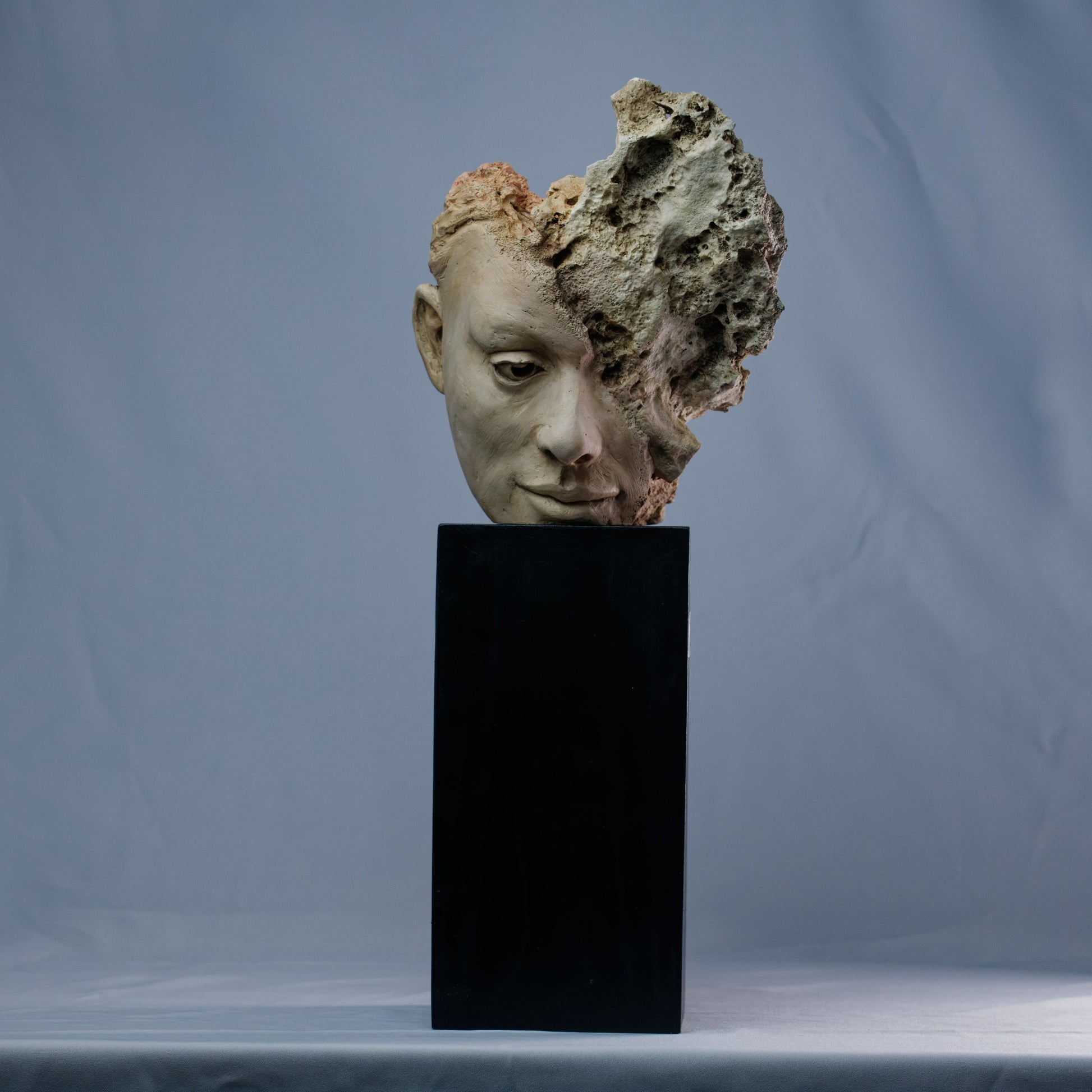 Obra escultórica contemporánea – mitad rostro humano, mitad roca con fragmentos de coral